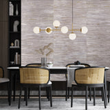 A modern dining room featuring a geometric patterned wallpaper in a subtle color palette, with a chandelier, bookshelves, and a round dining table with chairs.