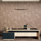 A modern office desk setup with a light wood and black desk, a black office chair, and a patterned beige wallpapered wall behind it.