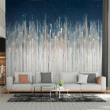 A large wall mural featuring an abstract vertical brushstroke pattern in navy blue, white, and light blue, styled behind a modern light gray sofa in a living room setting.